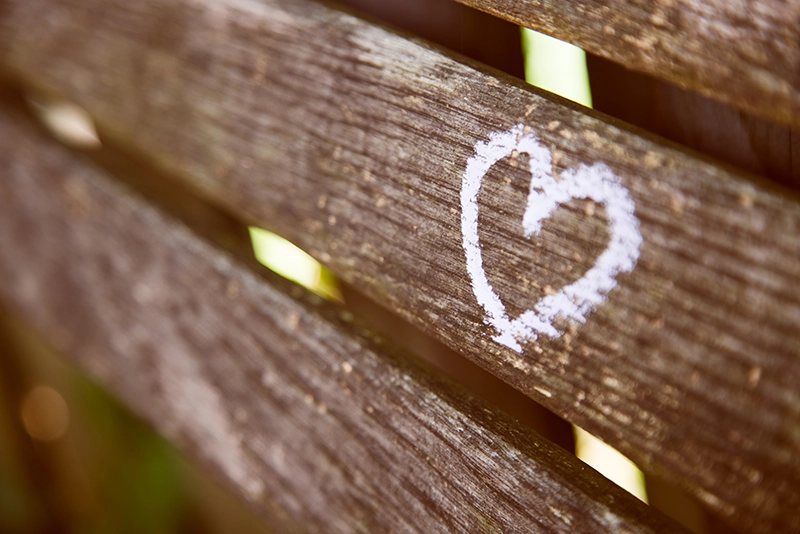 Un couple heureux qui a dessiné un cœur sur un banc.